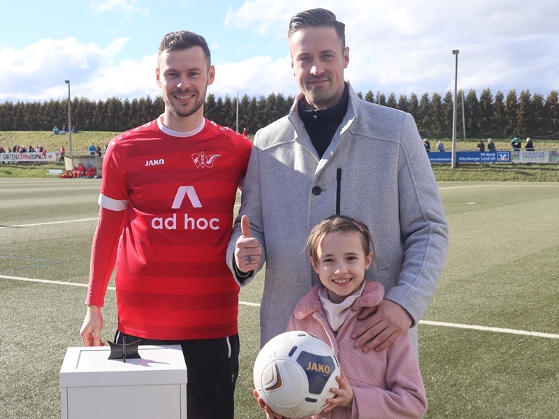 Sebastian Boge mit Spieler und Kind beim Sponsorenfoto auf dem Sportplatz des SV Schmölln.